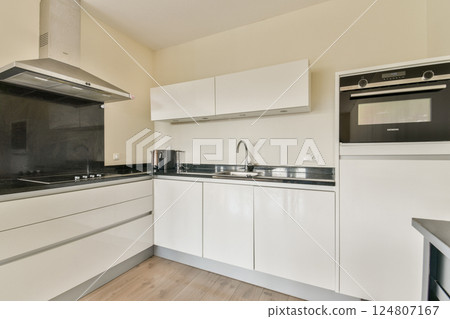 A contemporary kitchen featuring minimalist cabinetry, stainless steel appliances, and an open layout that maximizes space and functionality. Ideal for modern living. 124807167