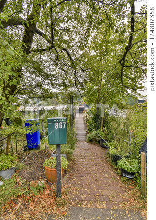A serene pathway leads through vibrant greenery, bordered by plants and a signpost, inviting exploration of the peaceful surroundings. A serene pathway leads through vibrant greenery, bordered by plants and a signpost, inviting exploration of the peaceful surroundings. 124807358