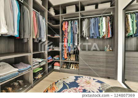 A contemporary closet design showcasing neatly organized clothes and accessories in an elegant setting, highlighting storage solutions and aesthetics. 124807369