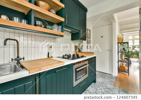 Modern kitchen design featuring green cabinetry, wooden shelves, and stylish accessories, blending functionality with aesthetic appeal. Modern kitchen design featuring green cabinetry, wooden shelves, and stylish accessories, blending functionality with aesthetic appeal. 124807395