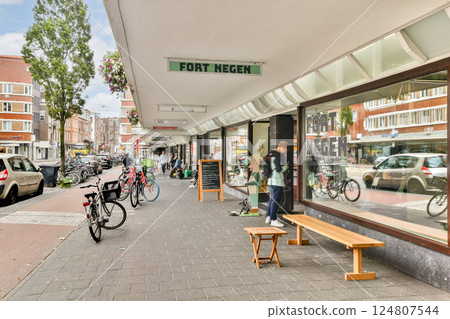 A lively urban scene showcasing bicycles parked along a vibrant street filled with shops and pedestrians on a sunny day. A lively urban scene showcasing bicycles parked along a vibrant street filled with shops and pedestrians on a sunny day. 124807544