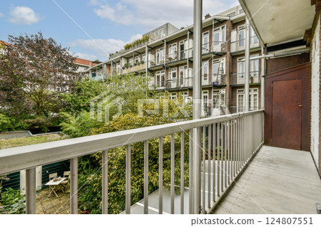A serene balcony view showcasing a blend of urban architecture and lush greenery, inviting relaxation and a connection to nature amidst city life. A serene balcony view showcasing a blend of urban architecture and lush greenery, inviting relaxation and a connection to nature amidst city life. 124807551