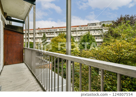 A serene modern balcony offering a view of lush trees and contemporary architecture in the distance. Perfect for relaxation and enjoying nature. A serene modern balcony offering a view of lush trees and contemporary architecture in the distance. Perfect for relaxation and enjoying nature. 124807554