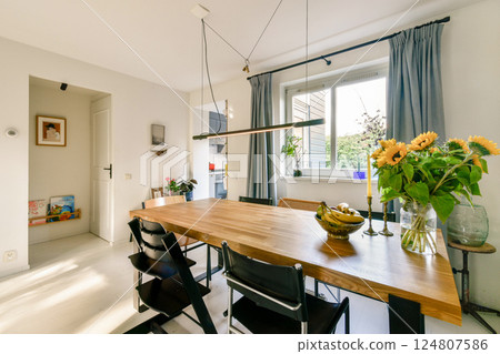 A bright and airy dining room showcasing a wooden table, elegant chairs, and fresh flowers, perfect for family gatherings and meals. A bright and airy dining room showcasing a wooden table, elegant chairs, and fresh flowers, perfect for family gatherings and meals. 124807586