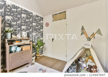 A charming children's room featuring playful elephant wallpaper, a cozy tent with stuffed animals, and decorative elements that create a warm atmosphere. 124807607
