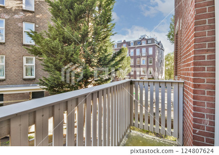 A charming balcony showcases a serene view of trees and urban architecture, blending nature and city life seamlessly. Perfect for relaxation and enjoying the surroundings. 124807624