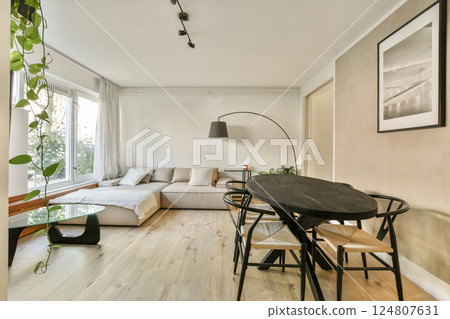 A trendy living room featuring a cozy sofa, contemporary dining table, and stylish decor elements, perfect for a comfortable yet chic environment. 124807631