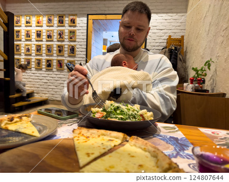 Father Holding Baby in Restaurant with Salad 124807644