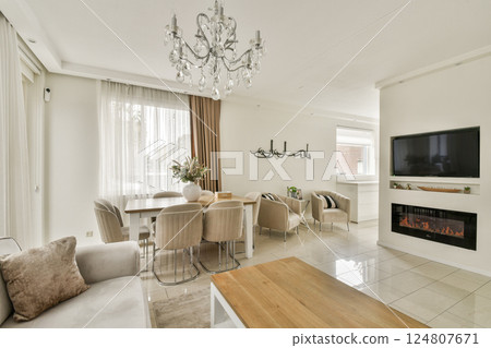 A stylish modern living room featuring a chandelier, contemporary furniture, and a cozy atmosphere with natural light and elegant decor. 124807671