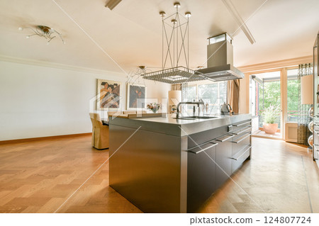 A sleek modern kitchen featuring stylish cabinets, a central island, and large windows that allow natural light to fill the space, enhancing its contemporary design. A sleek modern kitchen featuring stylish cabinets, a central island, and large windows that allow natural light to fill the space, enhancing its contemporary design. 124807724