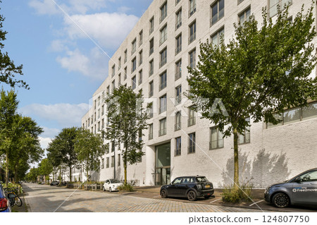 A contemporary building with a sleek facade and surrounding greenery, showcasing a blend of architecture and nature in an urban setting. A contemporary building with a sleek facade and surrounding greenery, showcasing a blend of architecture and nature in an urban setting. 124807750