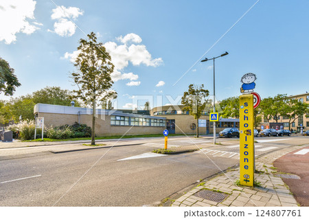 A vibrant school zone featuring a contemporary building design, surrounded by greenery and clear blue skies, ideal for promoting safe student activities. 124807761