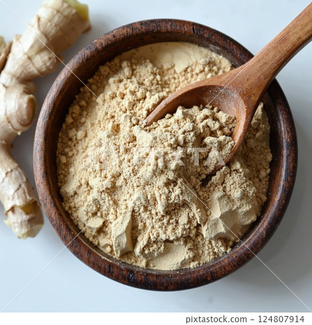 Aromatic ground ginger in rustic wooden bowl with spoon - organic spice for cooking, baking, and wellness 124807914