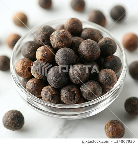 Aromatic whole black peppercorns in glass bowl on marble surface for culinary enhancement and spice enthusiasts 124807920
