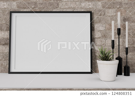 A modern interior space features a large blank picture frame positioned on a shelf. Complementing the frame are elegant candles and a small potted plant, enhancing the decor's simplicity. 3D render. 124808351