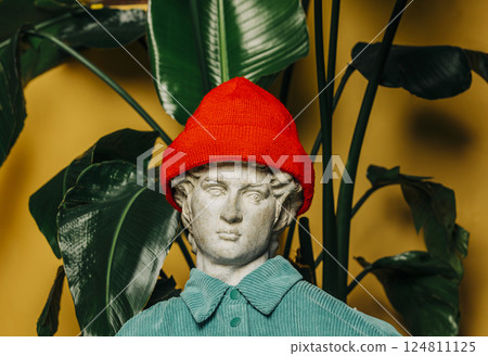 Antique statue  in a red hipster hat with a palm background 124811125