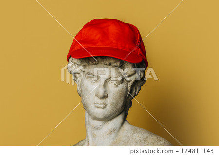 Bust of an antique statue of a young man wearing a red cap Bust of an antique statue of a young man wearing a red cap 124811143
