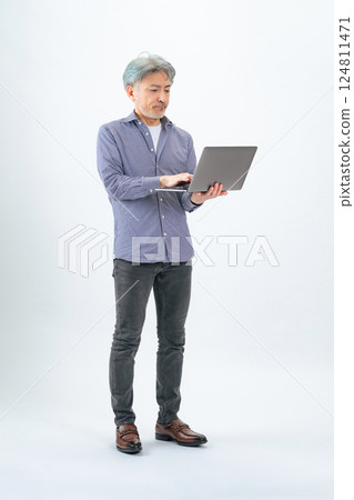 Full body photo of a senior man using a laptop Full body photo of a senior man using a laptop 124811471