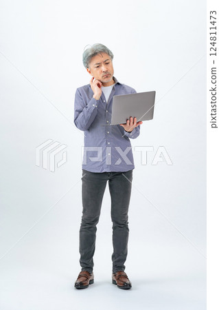 Full body photo of a senior man thinking with a laptop 124811473