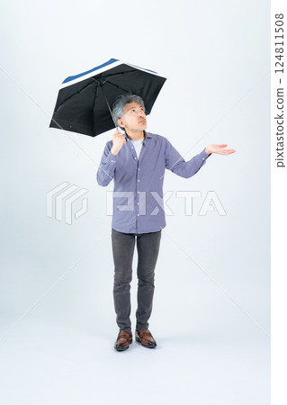 Full body photo of a senior man holding an umbrella Full body photo of a senior man holding an umbrella 124811508