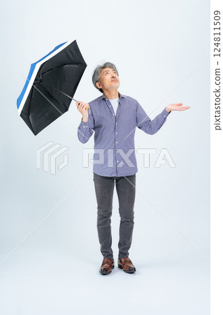 Full body photo of a senior man holding an umbrella Full body photo of a senior man holding an umbrella 124811509