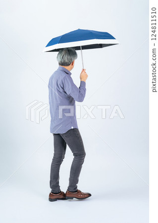Full-body photo of a senior man walking with a parasol Full-body photo of a senior man walking with a parasol 124811510