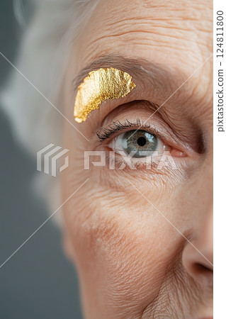 Captivating portrait of an elderly woman highlighted by delicate gold leaf on her skin, softened by ethereal lighting to create an elegant and surreal atmosphere 124811800