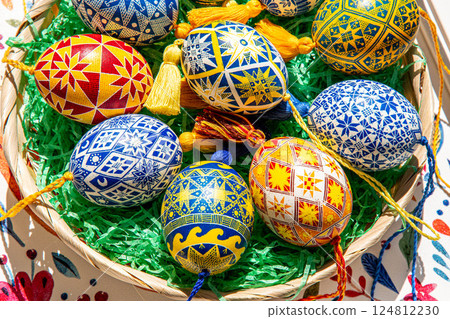 Colorful Easter eggs showcase traditional Ukrainian pysanky with intricate folk patterns in a charming Easter basket filled with green grass 124812230