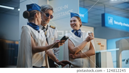 Professional Airline Captain Comes to Stewardesses in Airport Terminal 124812245