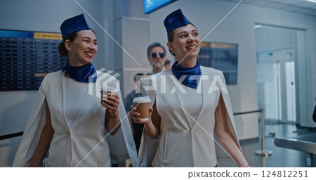 Airport Terminal: Two Flight Attendants Walking for Boarding Commercial Flight with Airline Pilot Airport Terminal: Two Flight Attendants Walking for Boarding Commercial Flight with Airline Pilot 124812251