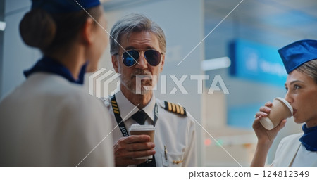Airline Captain in Glasses Talking to Two Beautiful Stewardesses in Airport Terminal Airline Captain in Glasses Talking to Two Beautiful Stewardesses in Airport Terminal 124812349