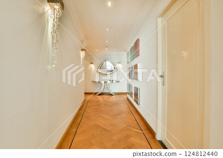 A stylish and well-lit modern hallway featuring elegant decor, wooden flooring, and a distinct mirror that enhances the spacious feel. 124812440