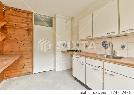 A compact kitchen featuring clean lines, wooden shelves, and minimalist cabinetry. Ideal for small spaces, it combines functionality with a stylish aesthetic. 124812486