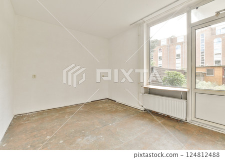 A bright, minimalist indoor area featuring a spacious layout and large window that offers an inviting view of greenery outside. 124812488