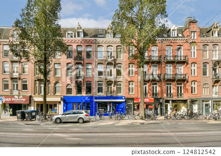 A picturesque view of traditional Amsterdam architecture featuring colorful buildings, parked bicycles, and a lively urban atmosphere reflecting daily life. A picturesque view of traditional Amsterdam architecture featuring colorful buildings, parked bicycles, and a lively urban atmosphere reflecting daily life. 124812542