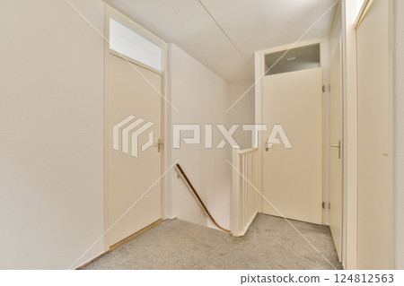 Bright and airy hallway showcasing a minimalist design with white walls and doors, accented by a subtle staircase. The clean lines create a sleek ambiance. Bright and airy hallway showcasing a minimalist design with white walls and doors, accented by a subtle staircase. The clean lines create a sleek ambiance. 124812563