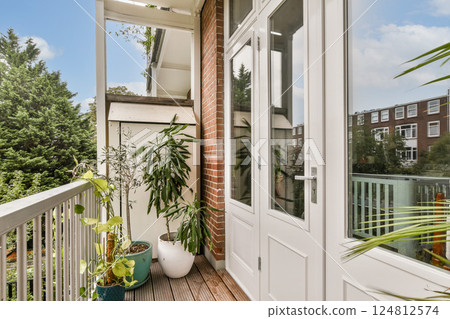 A stylish modern balcony featuring lush green plants and ample natural light, providing a serene outdoor space for relaxation and enjoyment. 124812574