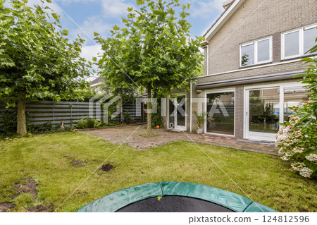 A serene garden featuring well-maintained greenery beside a contemporary home with large windows, emphasizing the blend of nature and modern architecture. A serene garden featuring well-maintained greenery beside a contemporary home with large windows, emphasizing the blend of nature and modern architecture. 124812596