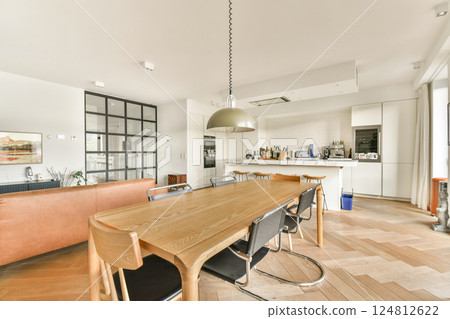 A spacious modern kitchen featuring minimalist design with a wooden dining table, sleek appliances, and ample natural light, creating an inviting culinary space. A spacious modern kitchen featuring minimalist design with a wooden dining table, sleek appliances, and ample natural light, creating an inviting culinary space. 124812622