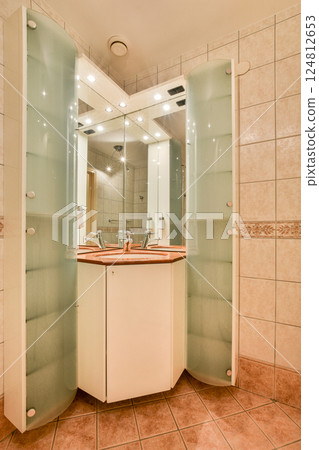 Elegant bathroom featuring a stylish vanity with dual sinks and a large mirror, surrounded by beautifully tiled walls and ambient lighting. 124812653