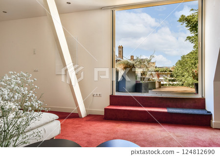 A contemporary living space featuring a large open window that showcases a lush outdoor view, complemented by elegant decor and bright, inviting colors. A contemporary living space featuring a large open window that showcases a lush outdoor view, complemented by elegant decor and bright, inviting colors. 124812690