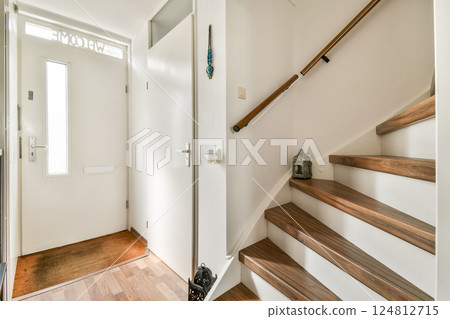 A modern entryway featuring a bright door, wooden stairs, and minimalist decor. The space is inviting and stylish, perfect for a contemporary home. A modern entryway featuring a bright door, wooden stairs, and minimalist decor. The space is inviting and stylish, perfect for a contemporary home. 124812715