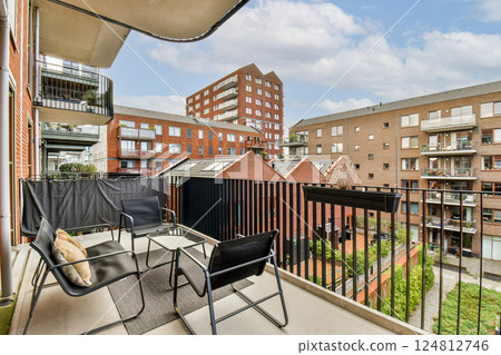 A stylish balcony overlooking contemporary apartment buildings and a vibrant courtyard, showcasing urban living and design aesthetics. A stylish balcony overlooking contemporary apartment buildings and a vibrant courtyard, showcasing urban living and design aesthetics. 124812746