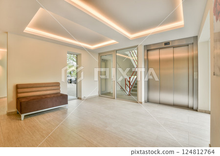 A spacious and well-lit modern entrance featuring a sleek elevator, comfortable seating, and contemporary design elements that create an inviting atmosphere. A spacious and well-lit modern entrance featuring a sleek elevator, comfortable seating, and contemporary design elements that create an inviting atmosphere. 124812764