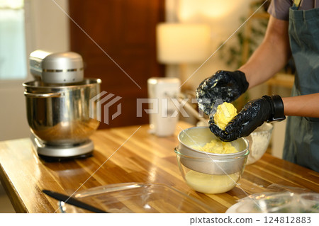 Man wearing black gloves squeezing out buttermilk from freshly churned butter 124812883