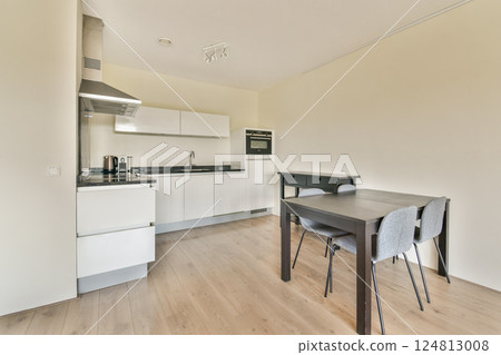 A sleek, modern kitchen featuring white cabinets, a black countertop, and minimalist design elements. Perfect for contemporary living spaces. 124813008