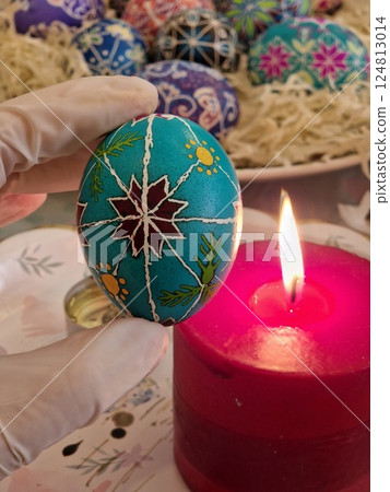 Crafting Easter egg using traditional Ukrainian pysanka technique with beeswax technique for intricate designs and folk patterns. Warming up Easter egg at candle Crafting Easter egg using traditional Ukrainian pysanka technique with beeswax technique for intricate designs and folk patterns. Warming up Easter egg at candle 124813014