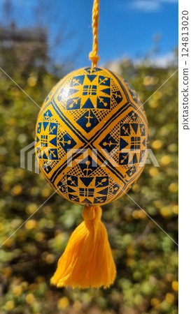 Vibrant traditional Ukrainian pysanka showcasing national colors yellow blue adorned with intricate patterns, celebrating Easter eggs and folk art traditions in a lively outdoor setting 124813020