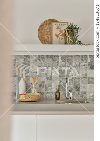 A stylish modern kitchen featuring a clean countertop, decorative items, and a sleek faucet, creating an inviting and contemporary space for cooking. 124813071