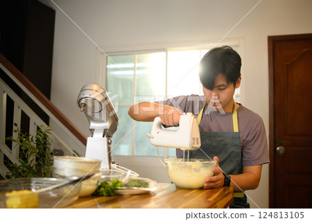 Man churning cream into butter with an electric mixer in a modern kitchen 124813105